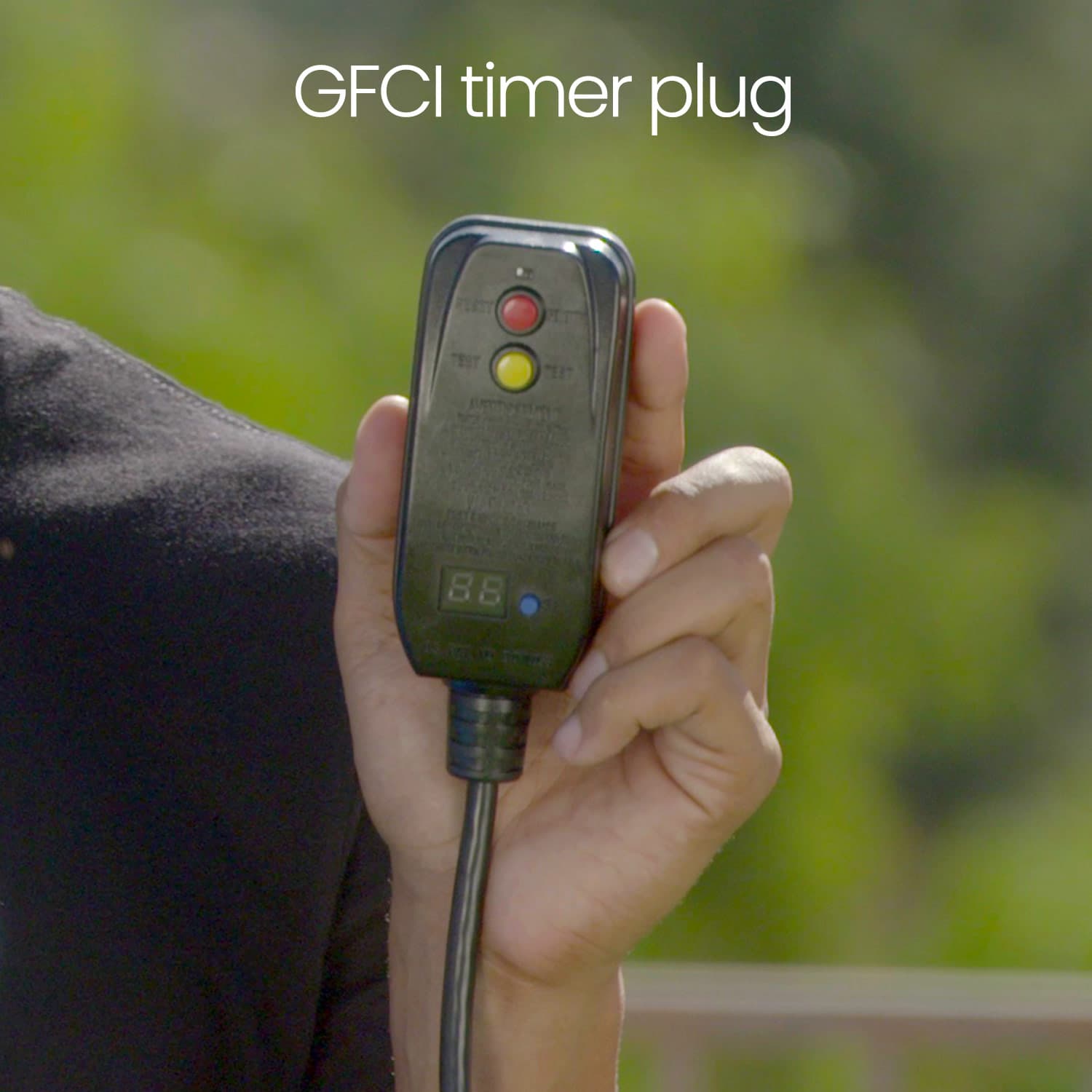 Hand holding a GFCI timer plug with a blurred green background