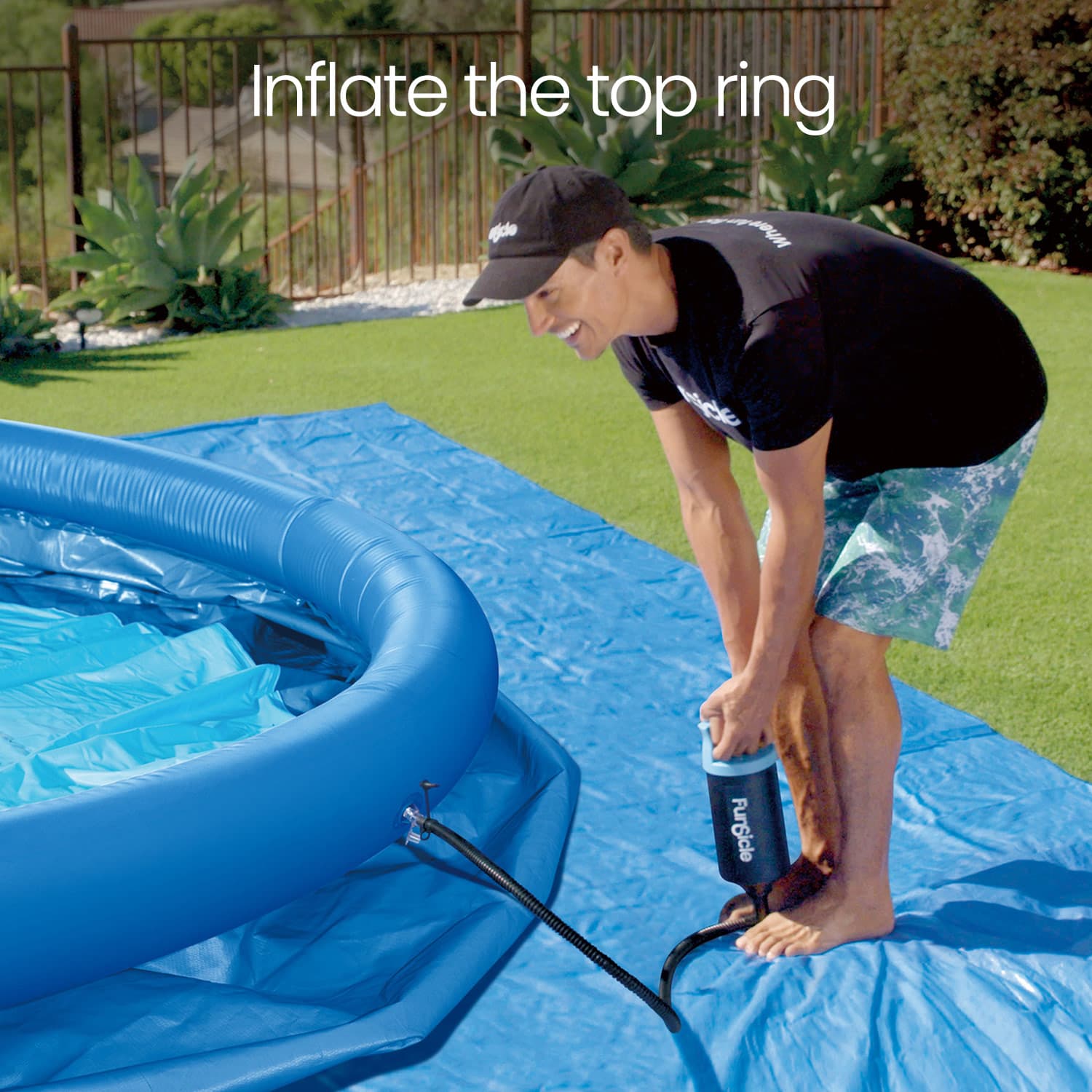 Person inflating a blue inflatable pool on a grassy area.