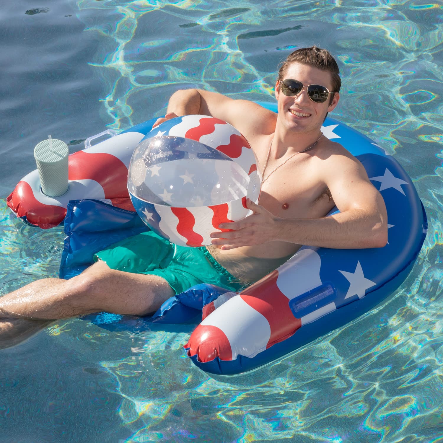 Man lounging on a patriotic inflatable pool float in clear blue water