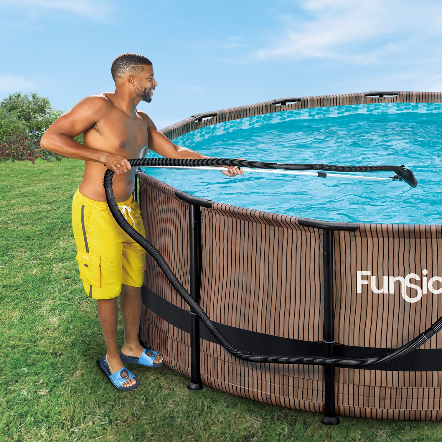 Man cleaning a pool with a vacuum hose, standing next to a FunSia pool.
